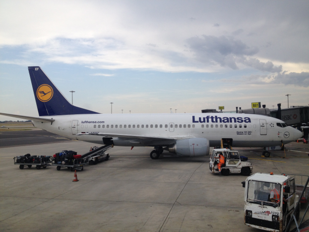 Lufthansa Airbus A320-200 am Frankfurter Flughafen mit Bodenfahrzeugen, Wagen, Verkehrskegeln, Beschilderung und einer bewölkten Himmel im Hintergrund.