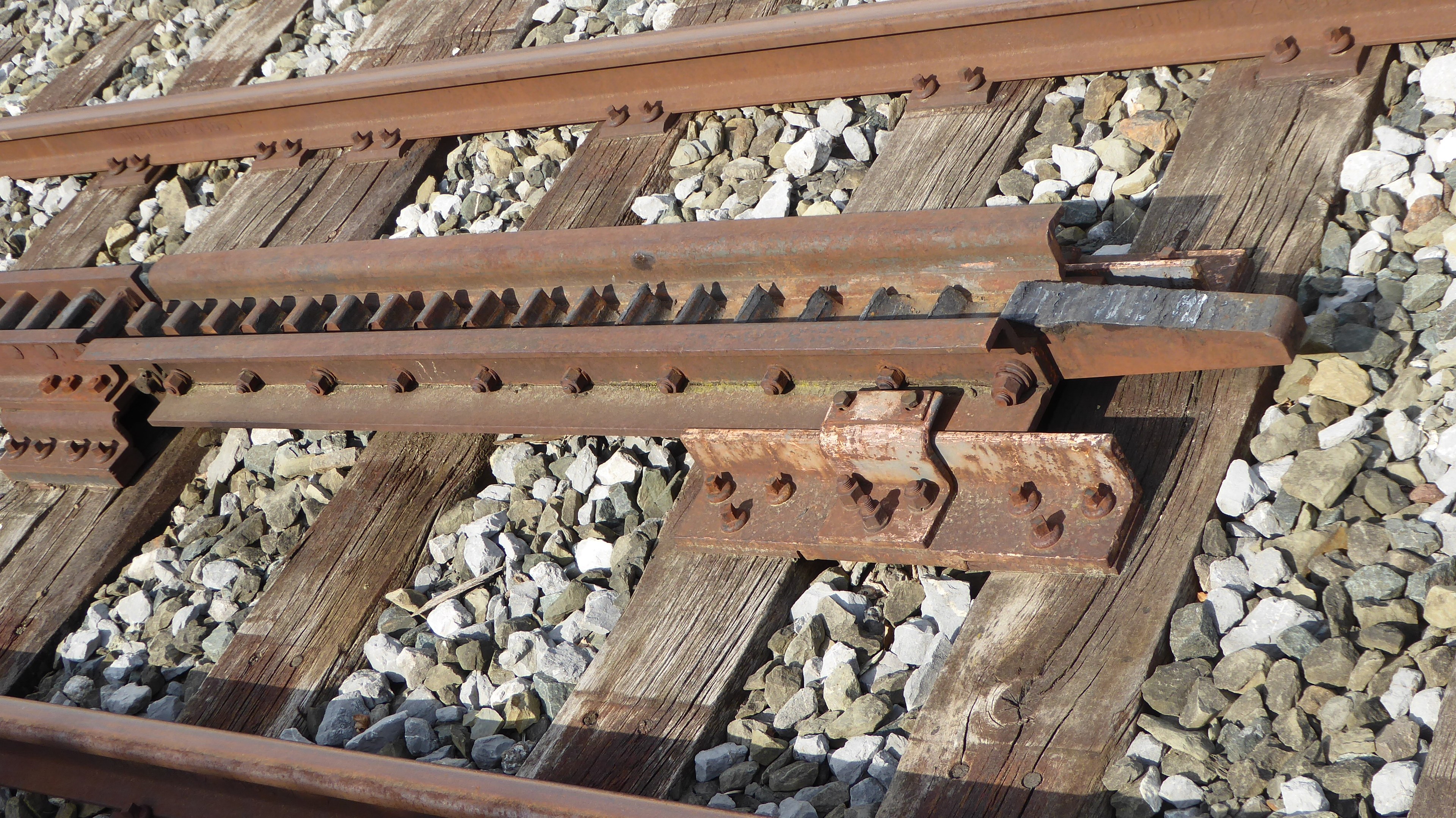 Nahaufnahme einer Schienenstrecke mit Metallschienen und umliegenden Steinen.