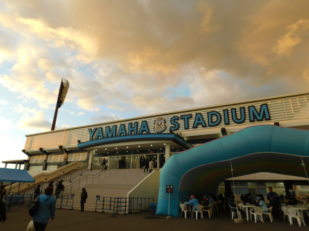 Yamaha-Stadion in San Francisco mit Menschen auf Sitzen und Stehen in der Nähe des Eingangs, Geländern, Stufen, einem Zelt auf der linken Seite und einer bewölkten Kulisse.