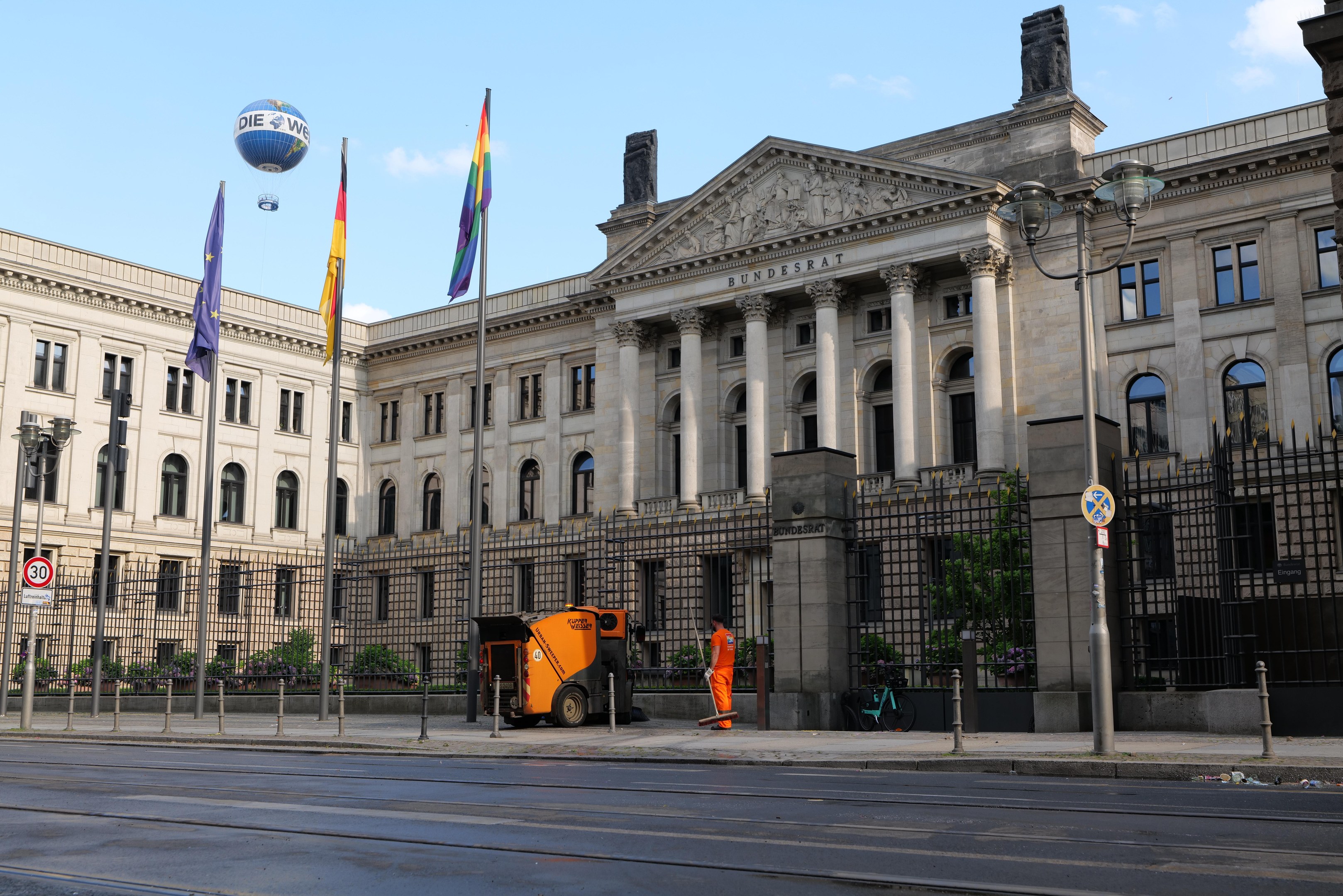 Großes modernes Regierungsgebäude mit vielen Fenstern, umgeben von Straßeninfrastruktur und Fußgängern, mit Flaggen vor dem Bundestag in Berlin, Deutschland.