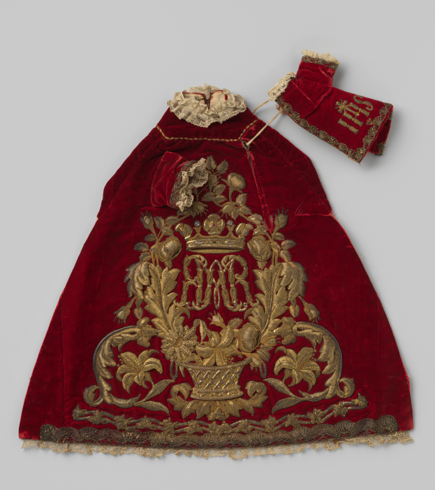 Ein roter Samtmantel mit goldener Stickerei und einer Kronenverzierung auf einem weißen Hintergrund, mit detaillierten königlichen Mustern.