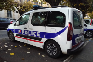 Polizeifahrzeug auf einer Stadtstraße mit Gebäuden, Bäumen und verstreuten Blättern geparkt.