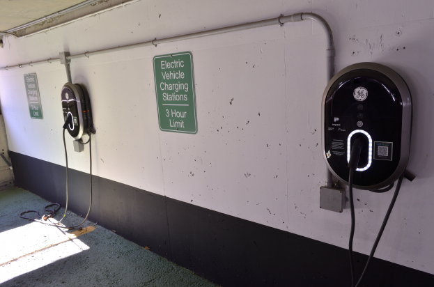 Ein Elektrofahrzeug-Ladestation in einer Parkgarage mit zwei an der Wand angebrachten Ladestationen und Tafeln mit Text darauf, der Boden ist unten im Bild sichtbar.