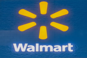 Blaue Wand mit dem Walmart-Logo in weißer Schrift, beleuchtet von hellem gelbem Licht.