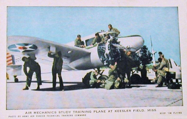 Gruppe von Menschen um ein Trainingsflugzeug auf einer Landebahn mit einem klaren blauen Himmel, Text unten lautet "Luftmechaniker-Studium Trainingsflugzeug auf Keesler Field, Miss."