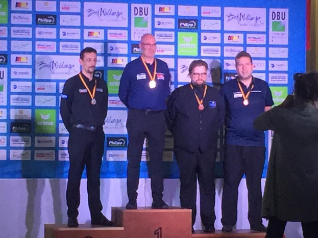 Fünf Medaillengewinner auf dem Podium bei der DDBU-Weltmeisterschaft 2019, mit einem Fotografen, der den Moment auf der rechten Seite einfängt.