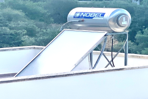 Solarwassererwärmer mit einem auf einem Gebäude installierten Speicher, Bäume im Hintergrund.