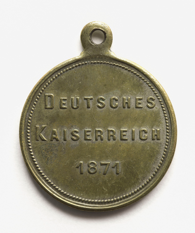 Eine Bronzemedaille mit der Inschrift "Deutsches Kaiserreich 1871" vor einem weißen Hintergrund.