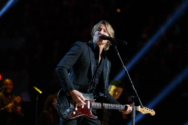Keith Urban performs auf der Bühne im Joint in Las Vegas, spielt eine Gitarre mit einem Mikrofon vor sich und Musiker im Hintergrund, unter dunkler Beleuchtung.