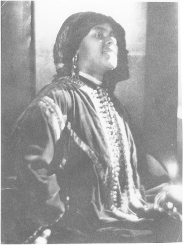 Schwarz-weiß-Foto einer Frau in Kleid und Schmuck vor einer Wand sitzend, mit der Bildunterschrift als erste indische Frau, die zum US-Präsidenten gewählt wurde.