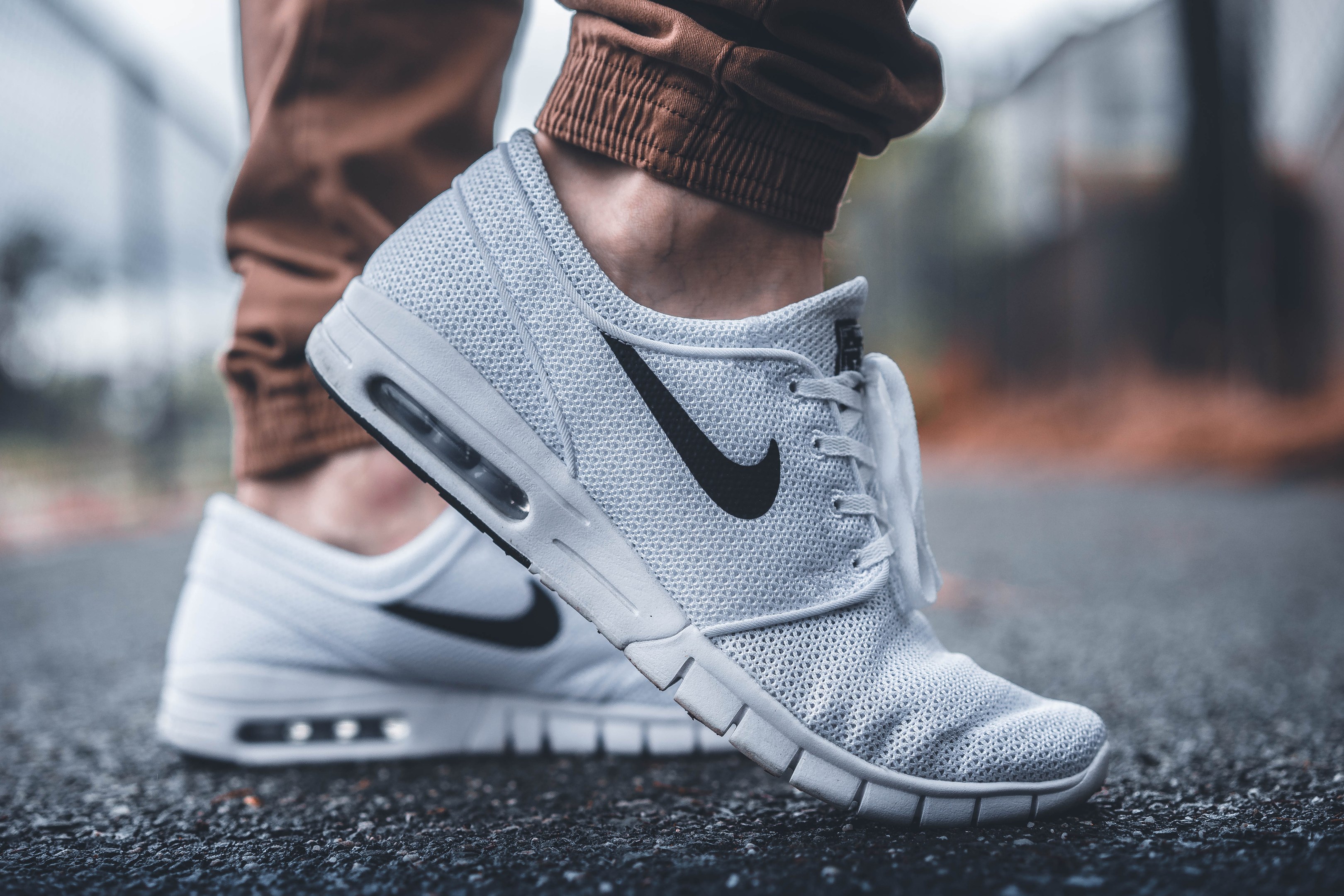 Eine Person in schwarzen und weißen Nike SB Stefan Janoski Max-Schuhen in Wolf Grau vor einem unscharfen, traumhaften Hintergrund.