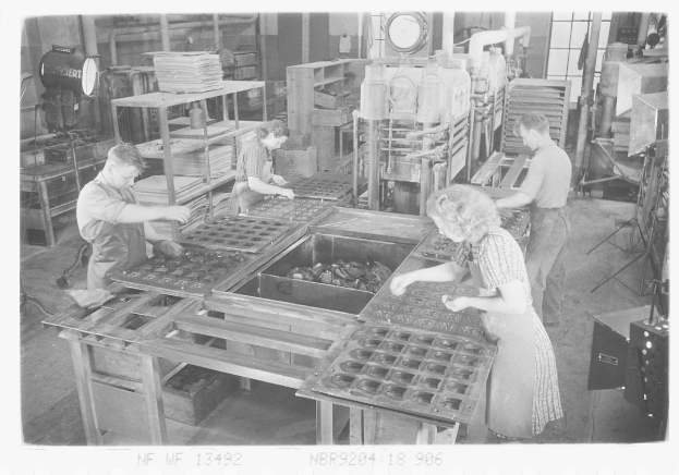 Schwarz-weißes Bild von Arbeitern, die Essensschalen in einer Fabrikumgebung zusammenbauen, mit Maschinen in der Hintergrund.