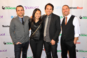 Eine Gruppe strahlender Personen, die vor der Kamera posieren und im Hintergrund ein Sponsorenbanner halten.